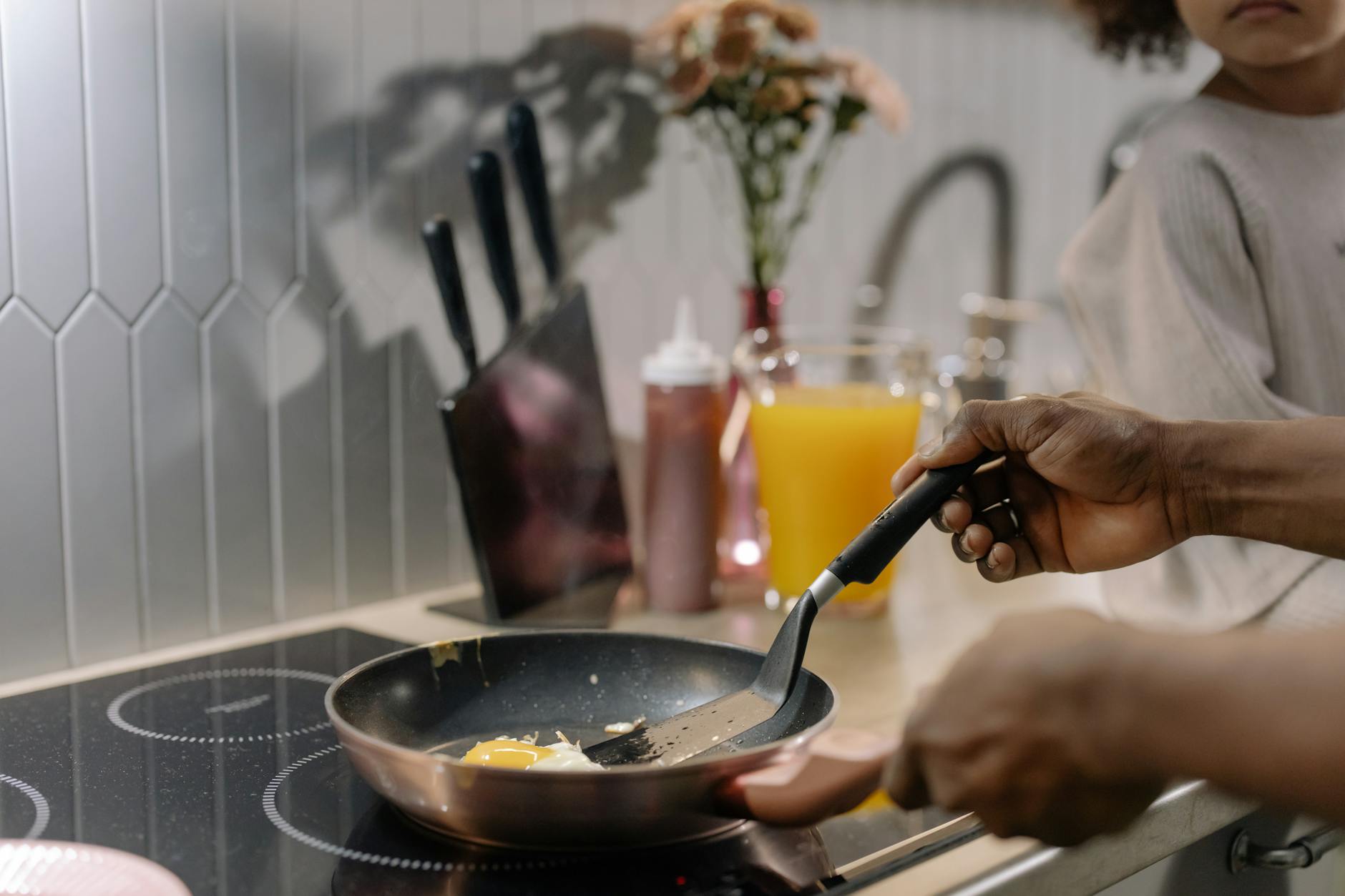Close-up of frying eggs on an induction stove during morning breakfast preparation.