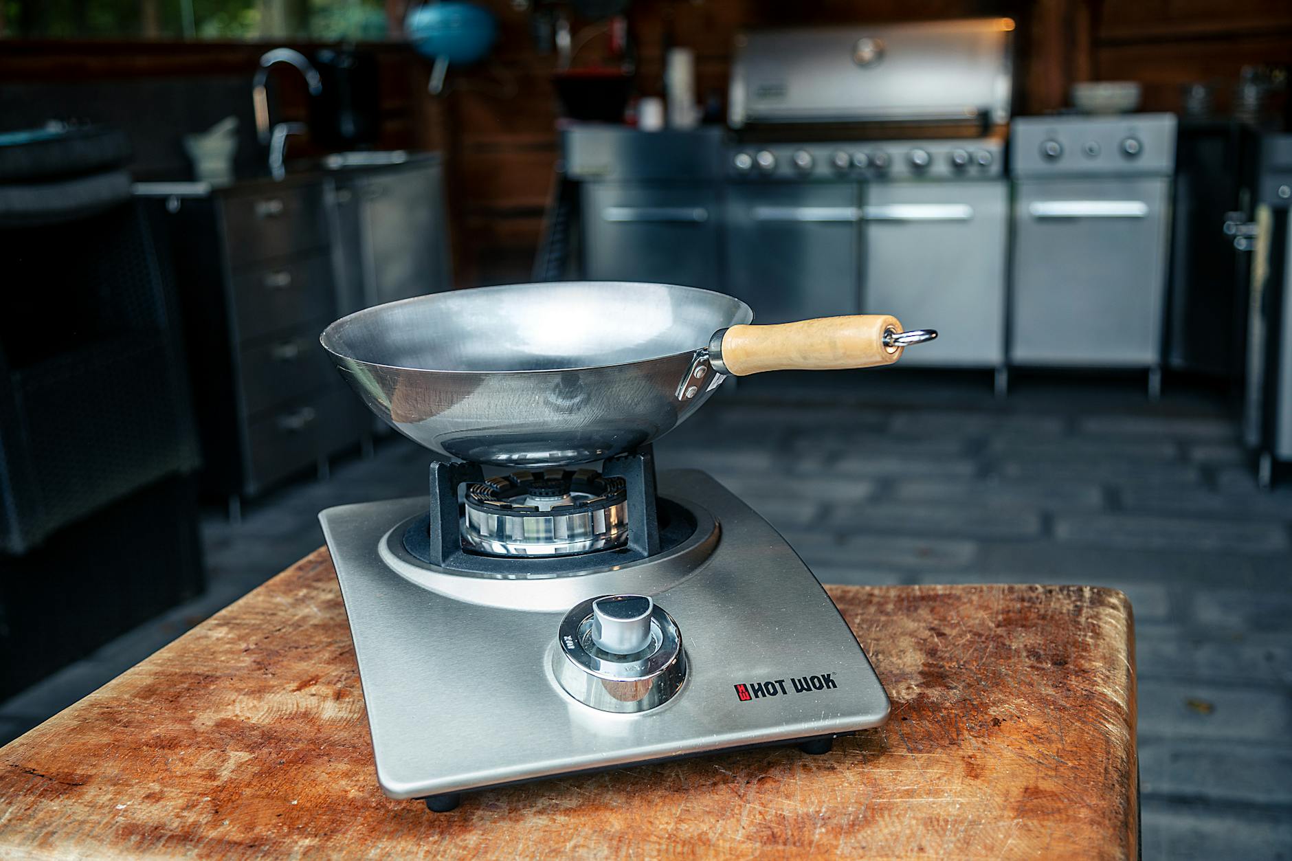 Close-up of a stainless steel wok on a wooden table in a kitchen setting, perfect for culinary themes.