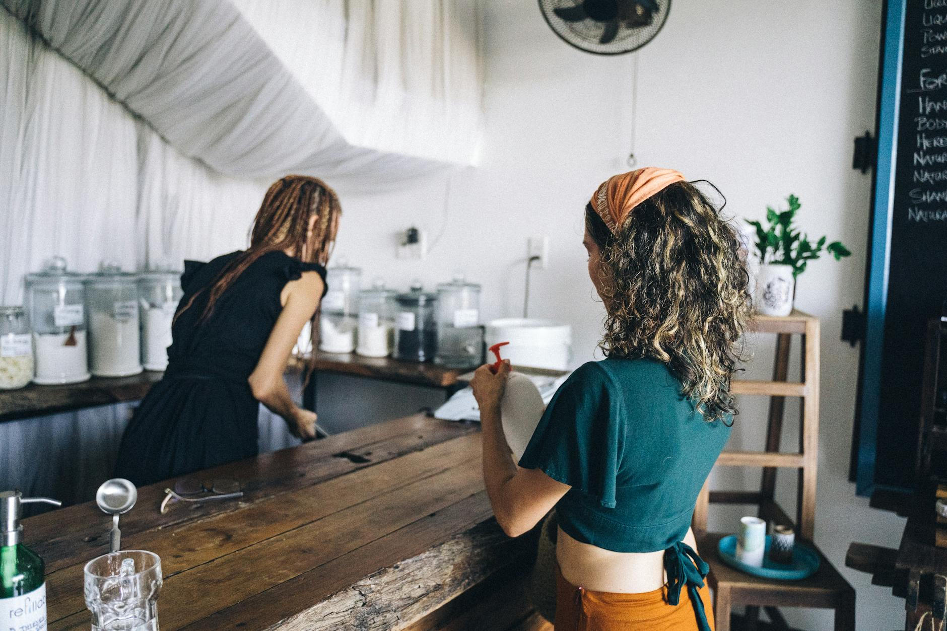 Women shopping in an eco-friendly store with refillable glass jars and sustainable practices.